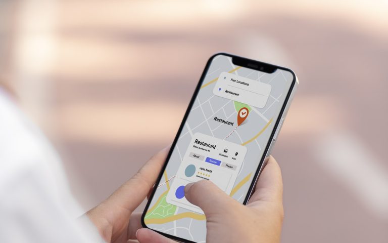 Hands holding a smartphone showing a map app with a restaurant place card and pin