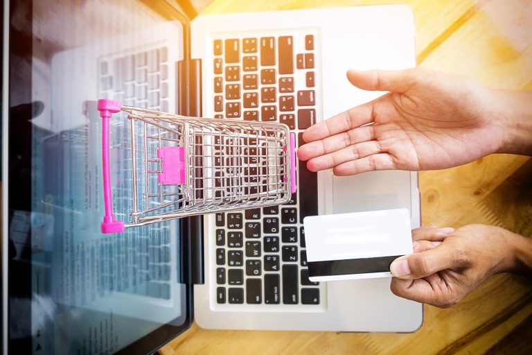 Shopper paying by card with a mini shopping cart on a laptop, the purchase moment where Amazon Sponsored Services ads appear